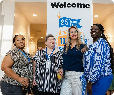 Four employees pose beneath a White Castle 25 Year Club welcome sign at a recognition event.