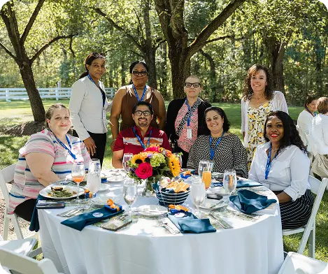 Employees gather around a decorated table during an outdoor White Castle 25 Year Club event.