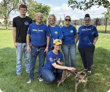 White Castle volunteers pose with a rescued dog during a community service event.