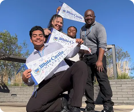 Four White Castle University graduates proudly display certificates outdoors after completing training.
