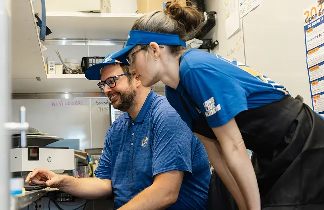 Two White Castle employees collaborate while working at a computer in the restaurant office.