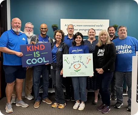 White Castle employees pose with kindness-themed signs during a community volunteer event.