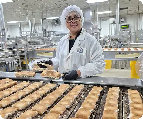 Food production worker inspects sliders on a conveyor line in a White Castle bakery facility.