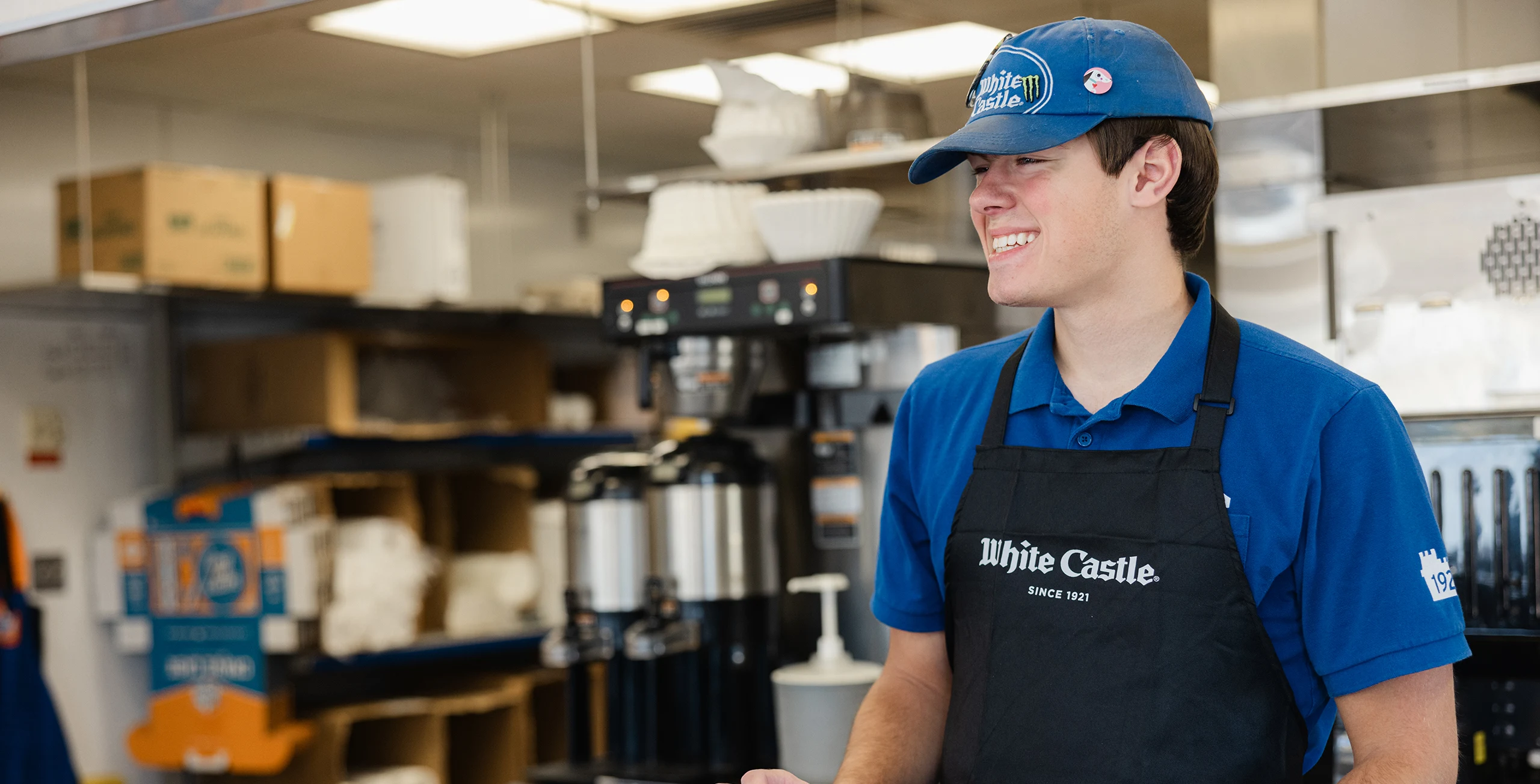 White Castle team member in black apron smiles while standing behind the restaurant counter.