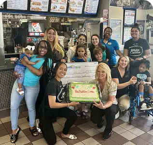 White Castle team members present a donation check and cake with families at a community celebration.